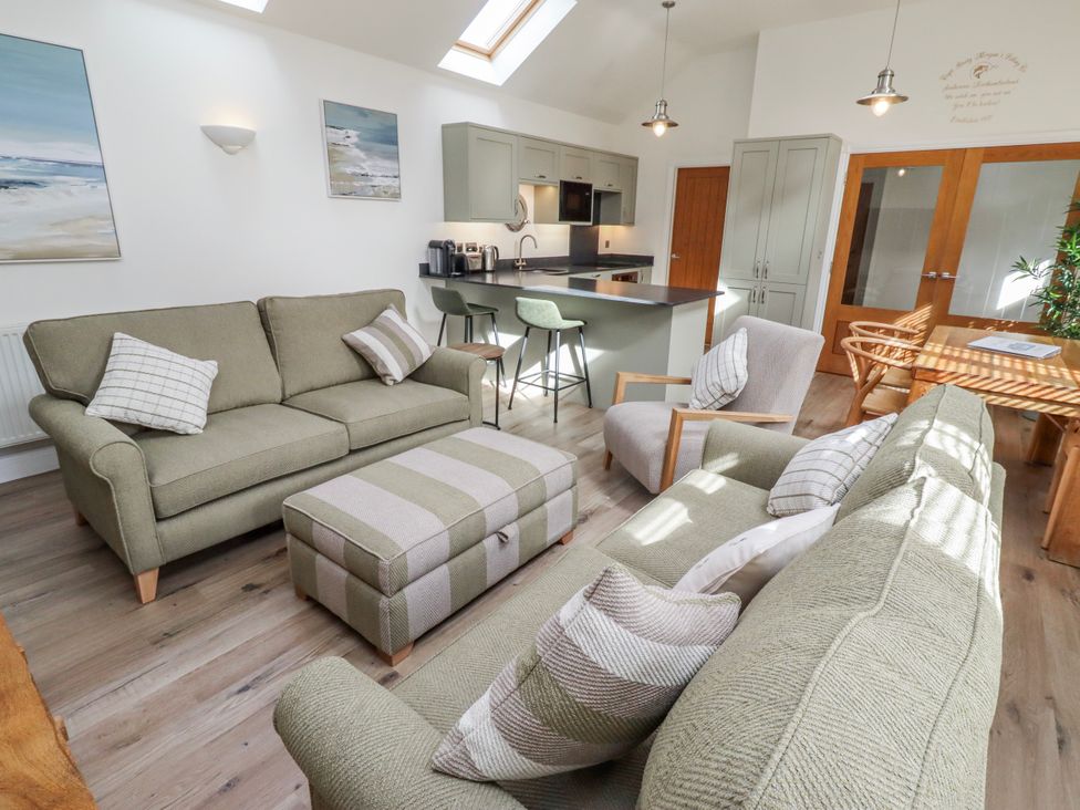 A living room with a sofa and kitchen island at Hideaway Cottage No 1 Seahouses