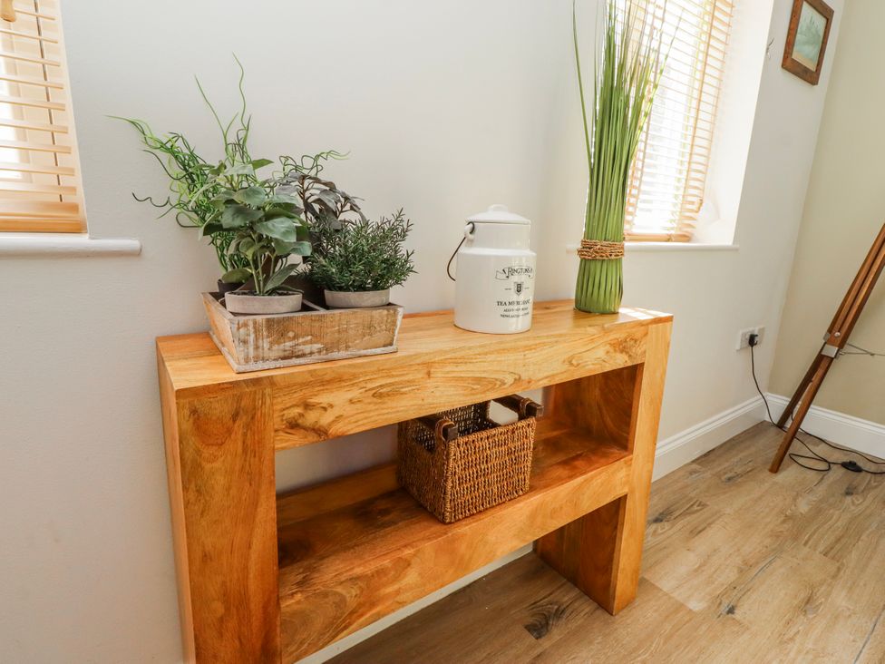 A console table with potted plants and a tin canister at Hideaway Cottage No 1 Seahouses