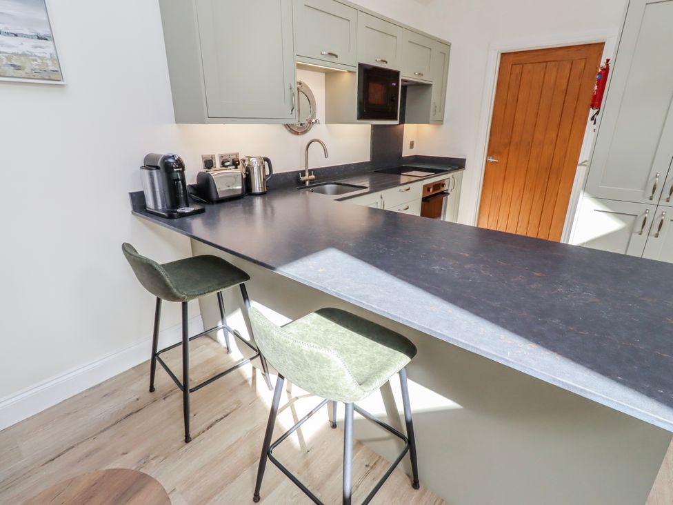 A kitchen with a counter and stools at Hideaway Cottage No 1 Seahouses