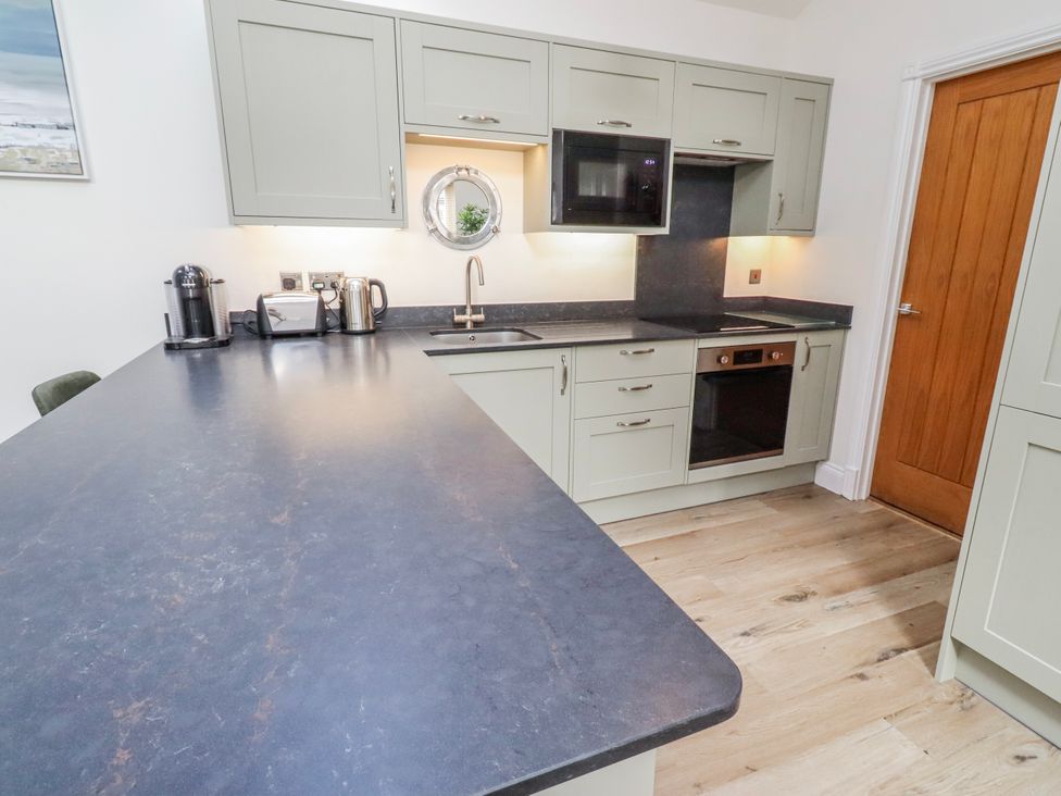 A kitchen with cabinets and appliances at Hideaway Cottage No 1 Seahouses