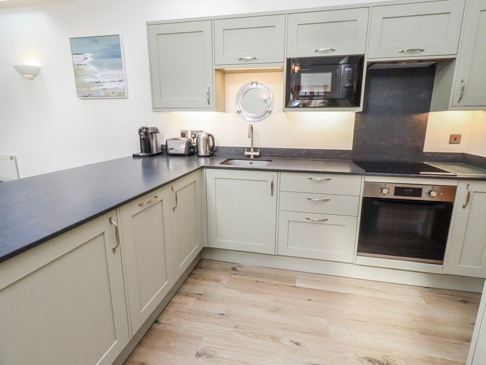 A kitchen with cabinets and appliances at Hideaway Cottage No 1 Seahouses