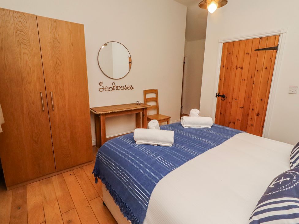 A bedroom with a bed and wardrobe at Hideaway Cottage No 1 Seahouses