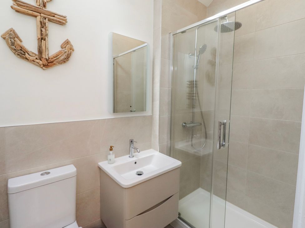 A bathroom with a shower, sink, and toilet at Hideaway Cottage No 1 in Seahouses