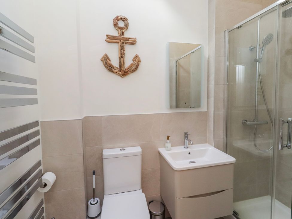A bathroom with toilet, sink, shower and mirror at Hideaway Cottage No 1 in Seahouses