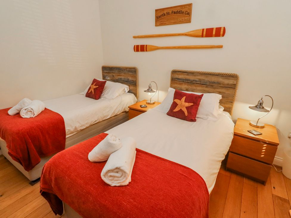 A bedroom with two beds and wooden decorations at Hideaway Cottage No 1 Seahouses