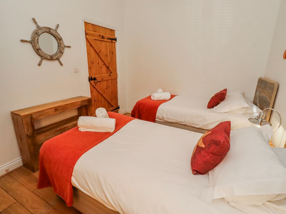 A bedroom with two beds and a wooden door at Hideaway Cottage No 1 in Seahouses