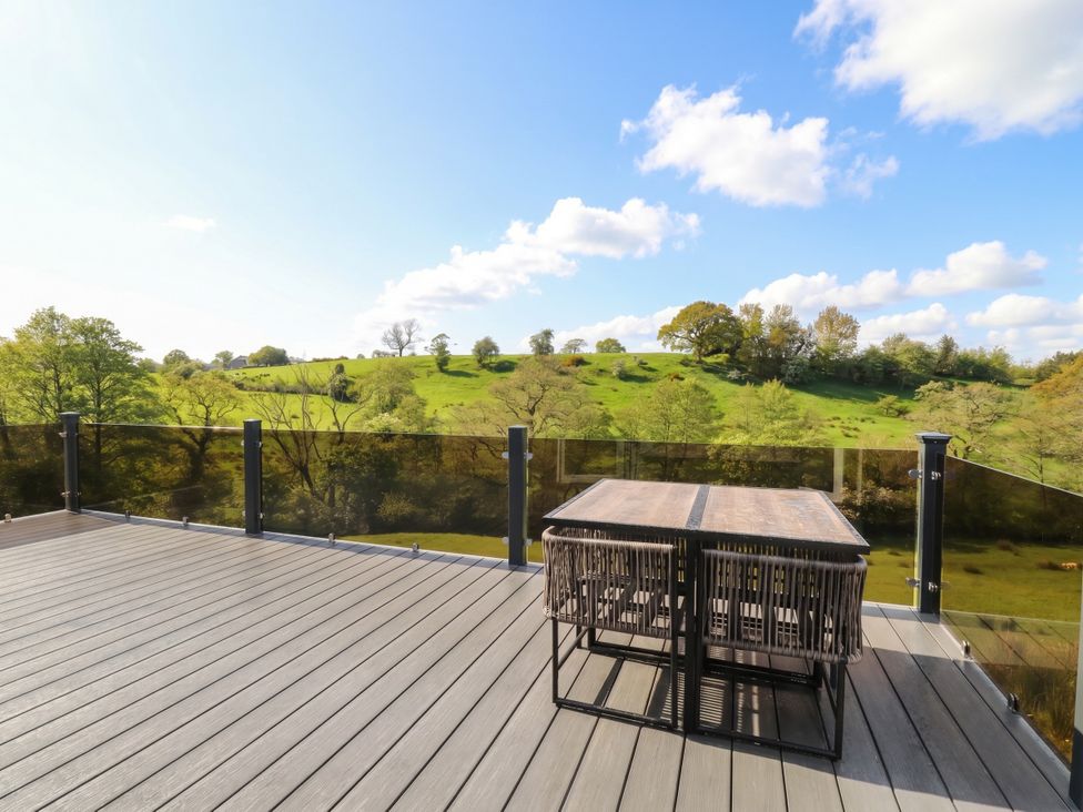 An outdoor deck with a table and chairs overlooking a green hillside at Number 35 in 