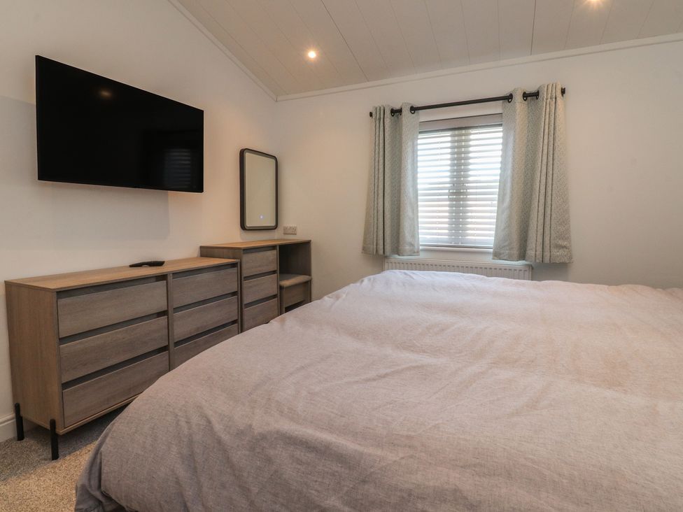 A bedroom with a bed, dresser, mirror, and television at Number 35