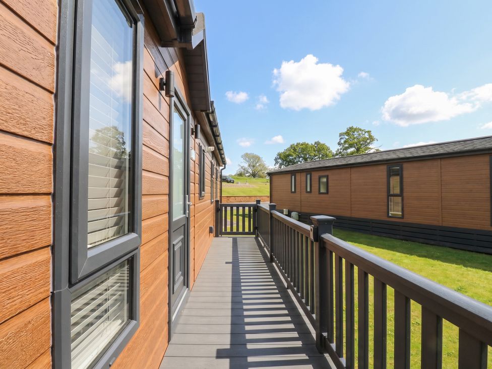 A deck area with grass and two wooden buildings at Number 35