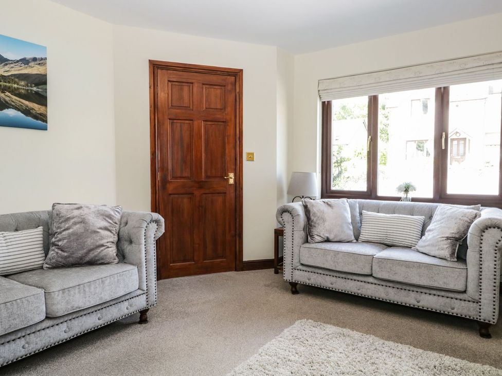 A living room with two sofas and a door at Dolly Blue Backbarrow near Newby Bridge