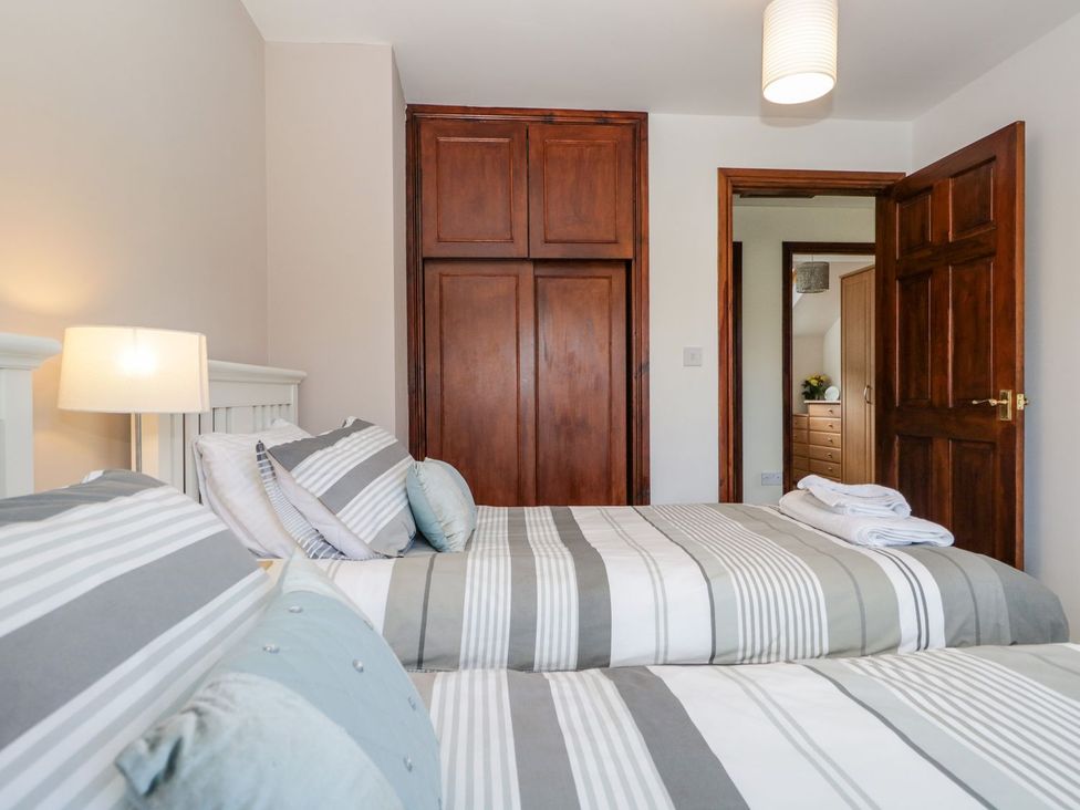 A bedroom with two beds and a wardrobe at Dolly Blue Backbarrow near Newby Bridge