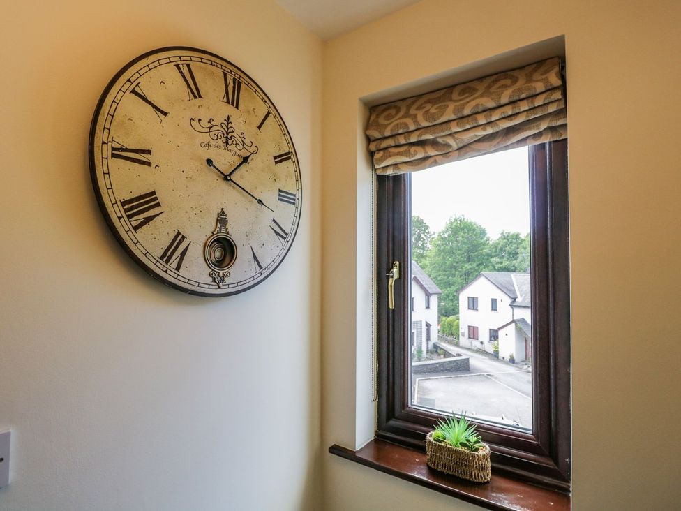 A window with a clock and plant in the hallway at Dolly Blue, Backbarrow near Newby Bridge
