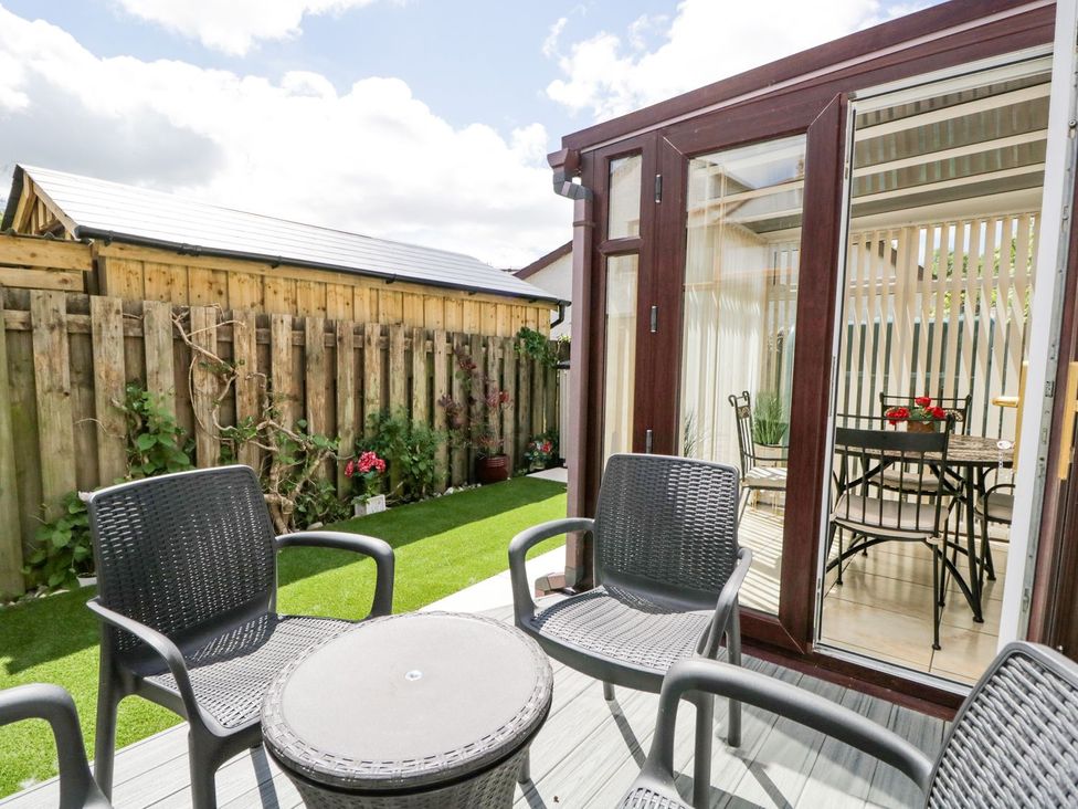 An outdoor seating area with chairs and a table at Dolly Blue Backbarrow near Newby Bridge
