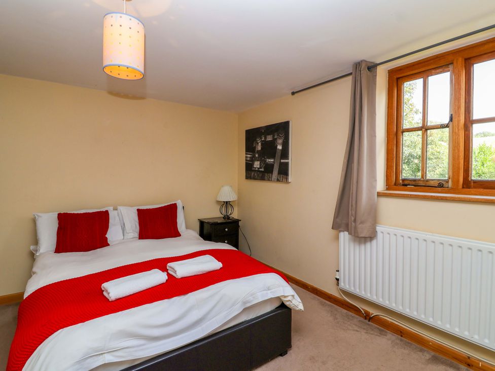 A bedroom with a bed and a window at Millbarn in Crowcombe