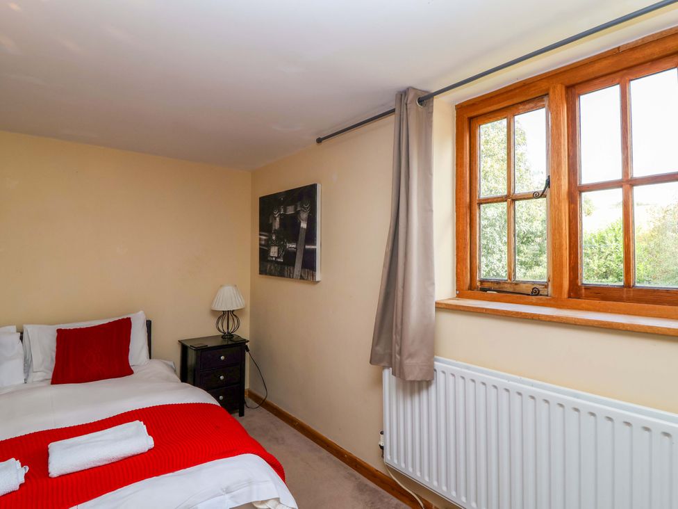 A bedroom with a bed and window at Millbarn in Crowcombe