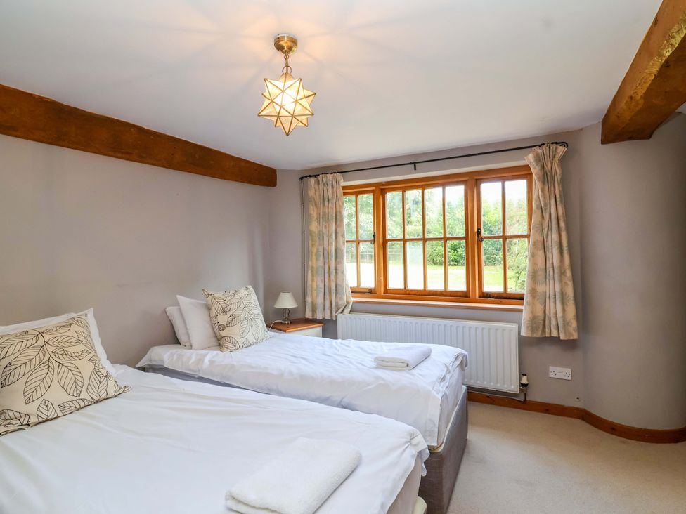 A bedroom with two beds and a window at Millbarn in Crowcombe