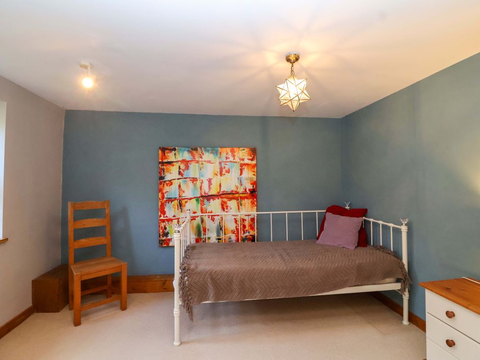 A bedroom with a bed, chair, and painting at Millbarn in Crowcombe