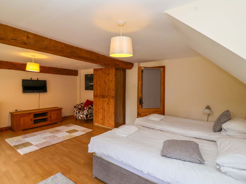A bedroom with beds and a television at Millbarn in Crowcombe