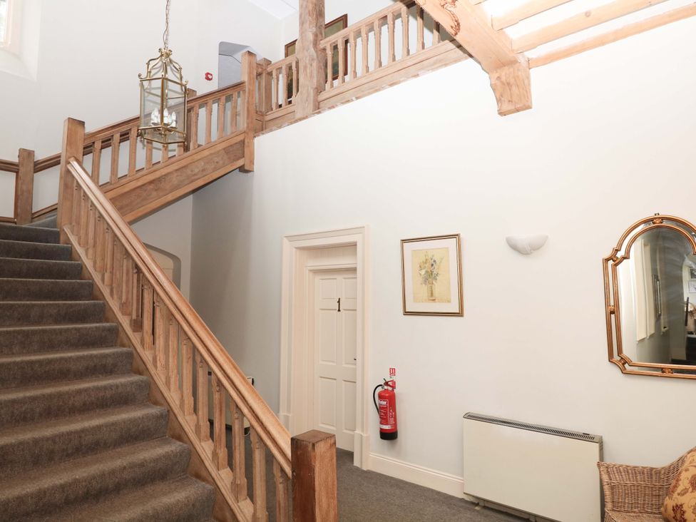 A staircase with wooden handrail and artwork in a hallway at 2 Sheplegh Court Blackawton near Dartmouth