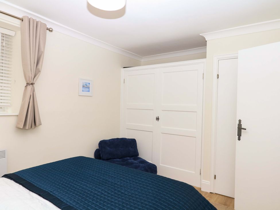 A bedroom with a blue quilt and a chair at 2 Sheplegh Court Blackawton near Dartmouth