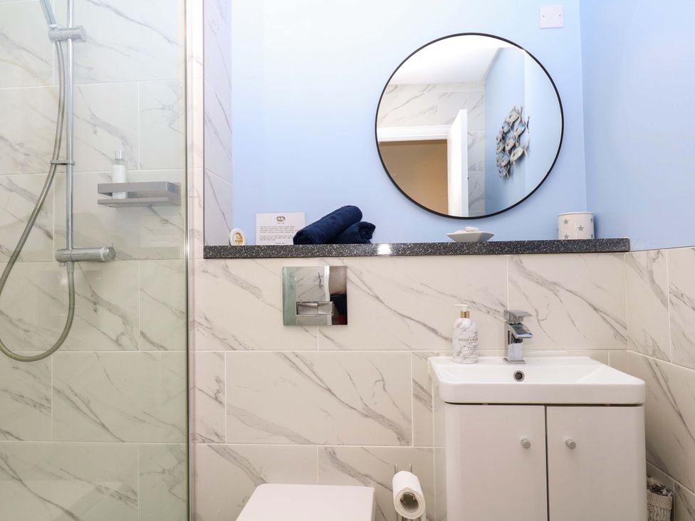 A bathroom featuring a shower, toilet, sink, and mirror at 2 Sheplegh Court Blackawton near Dartmouth