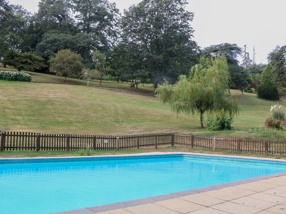 An outdoor swimming pool with a fenced area at Sheplegh Court Garden Apartment Blackawton near Dartmouth