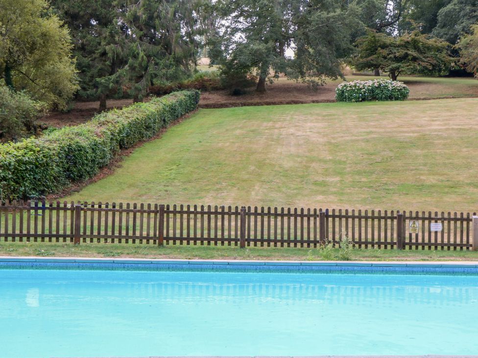 An outdoor area with a swimming pool and fence at Sheplegh Court Garden Apartment Blackawton near Dartmouth