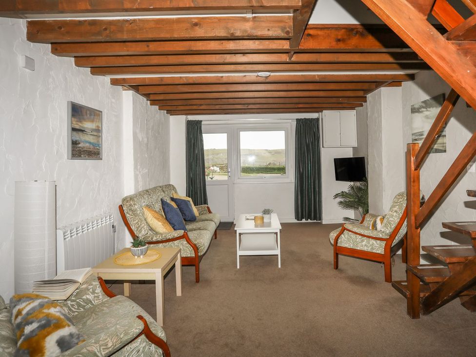 A living room with sofas, a coffee table, and a television at Fadrun - 3 Ty'n Don