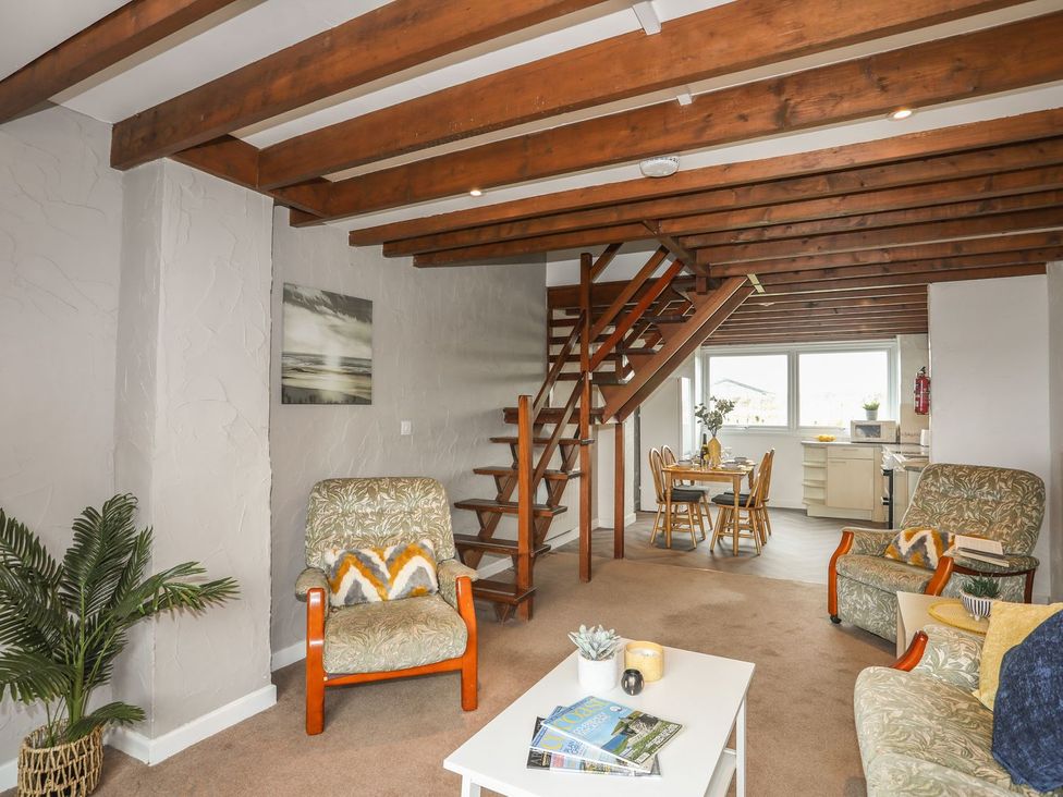 A living room with a staircase and dining area in Fadrun - 3 Ty'n Don