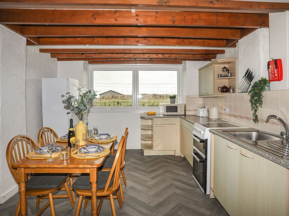 A kitchen with a dining table and chairs at Fadrun - 3 Ty'n Don