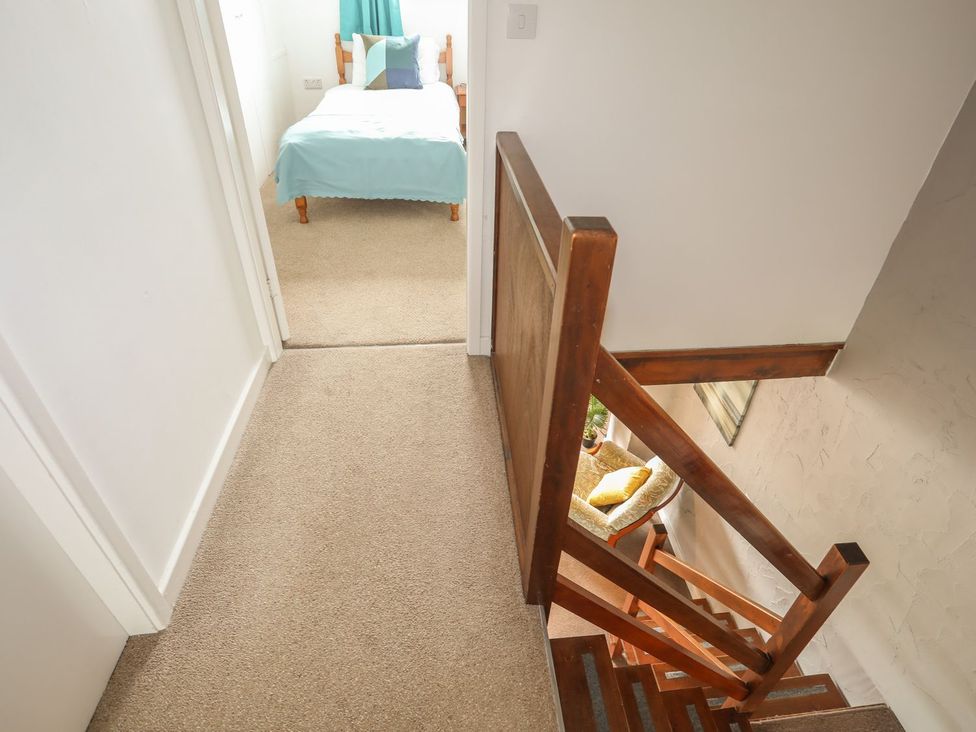 A hallway with a staircase leading down and a bedroom at Fadrun - 3 Ty'n Don