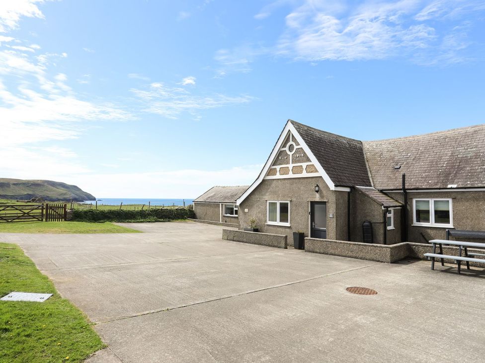 A building with a driveway and grass near the ocean at Fadrun - 3 Ty'n Don