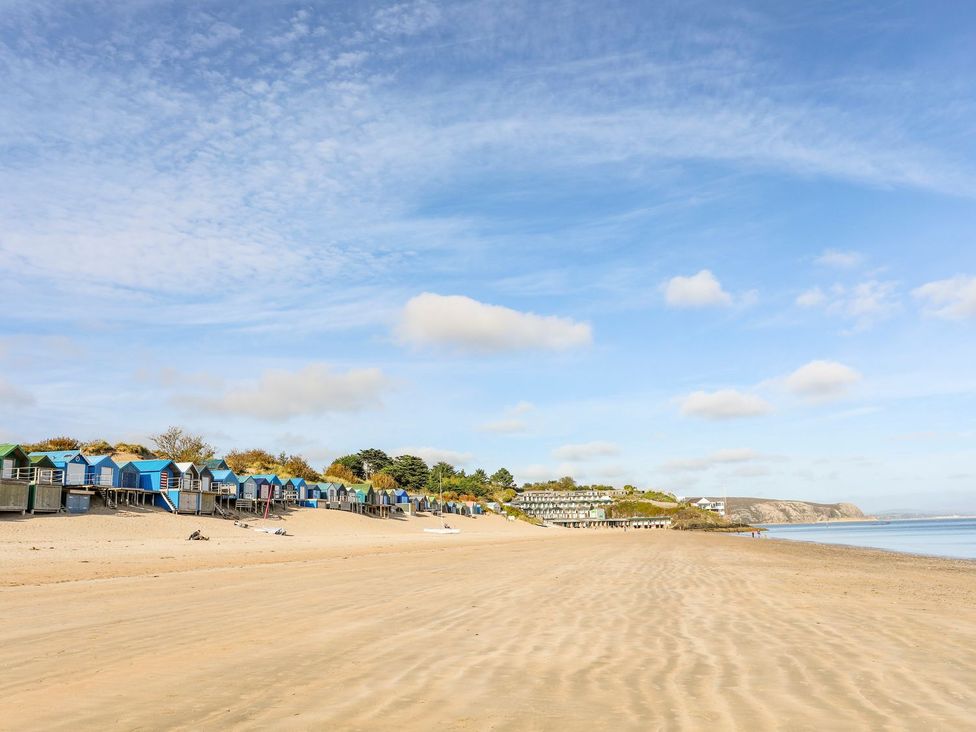 A beach with colorful beach huts and sand at Fadrun - 3 Ty'n Don