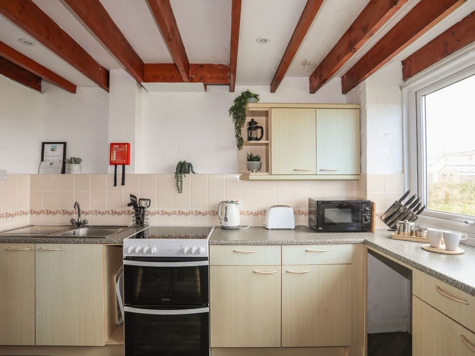 A kitchen with appliances and cabinets at Penrhyn - 4 Ty'n Don