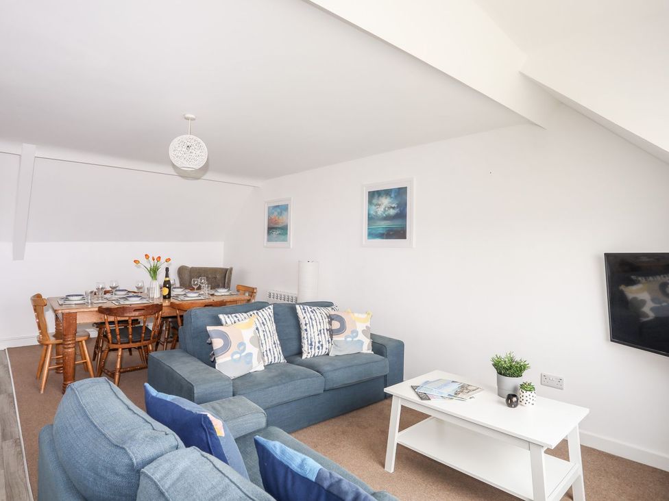A living room with a sofa and dining table at Towyn - 7 Ty'n Don