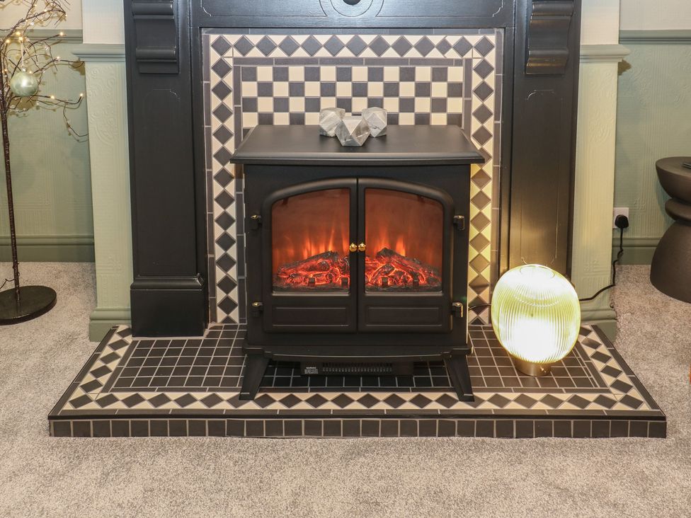 A fireplace with an electric heater and decorative stones at Franbols Cottage in Shelf