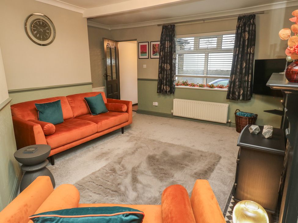 A living room with an orange sofa and a TV at Franbols Cottage in Shelf