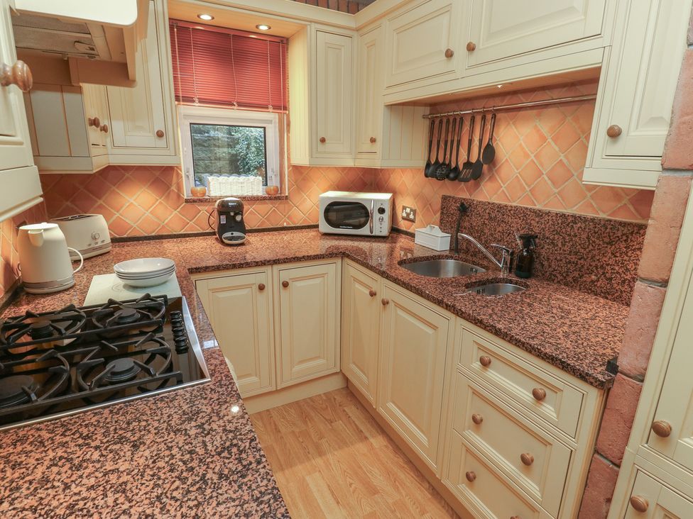 A kitchen with a gas stove, microwave and sink at Franbols Cottage in Shelf