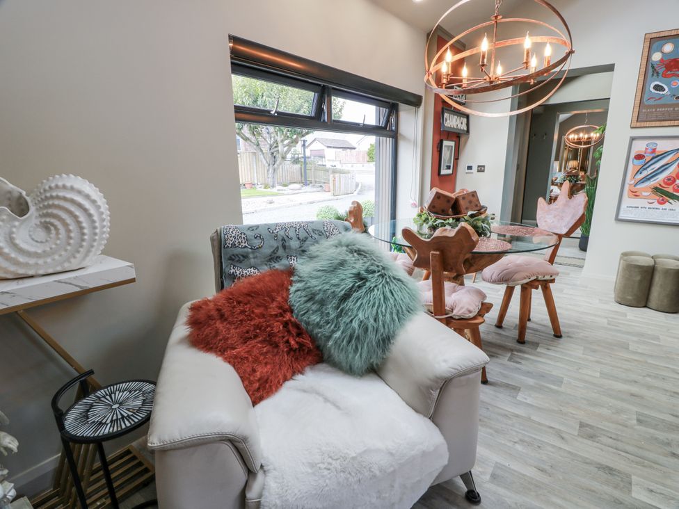 A living room with an armchair and dining table at Scotia At The Brig Annan