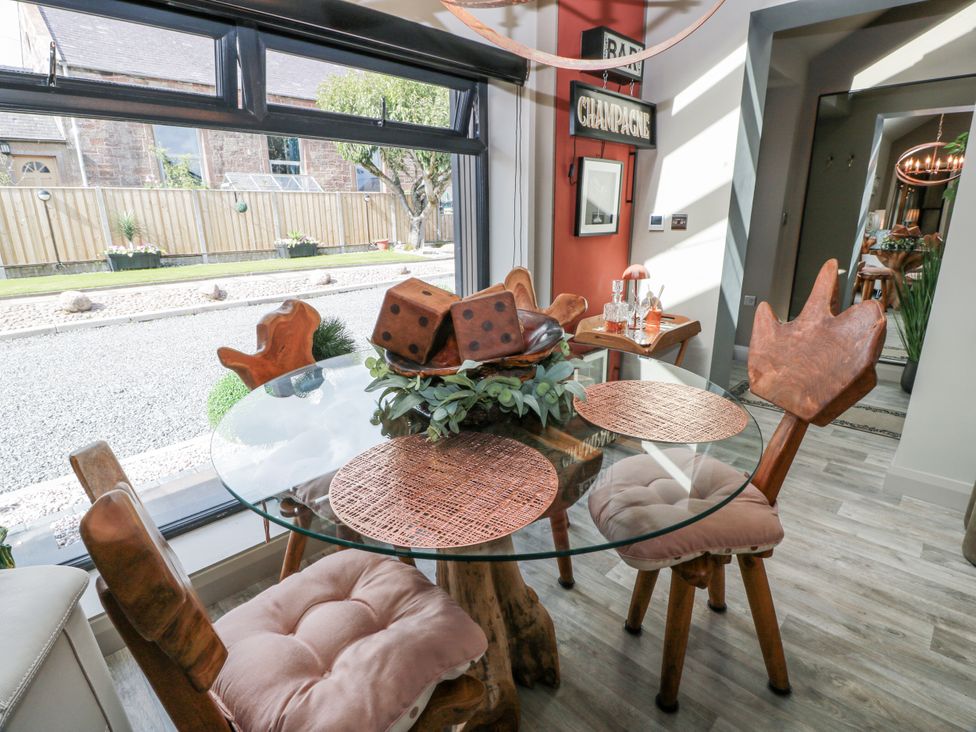 A dining room with a glass table and wooden chairs at Scotia At The Brig Annan