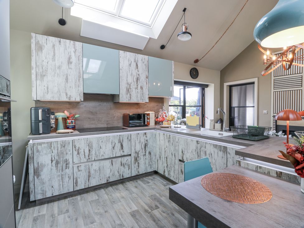 A kitchen with cabinets, a counter, a sink, and a dining table at Scotia At The Brig Annan