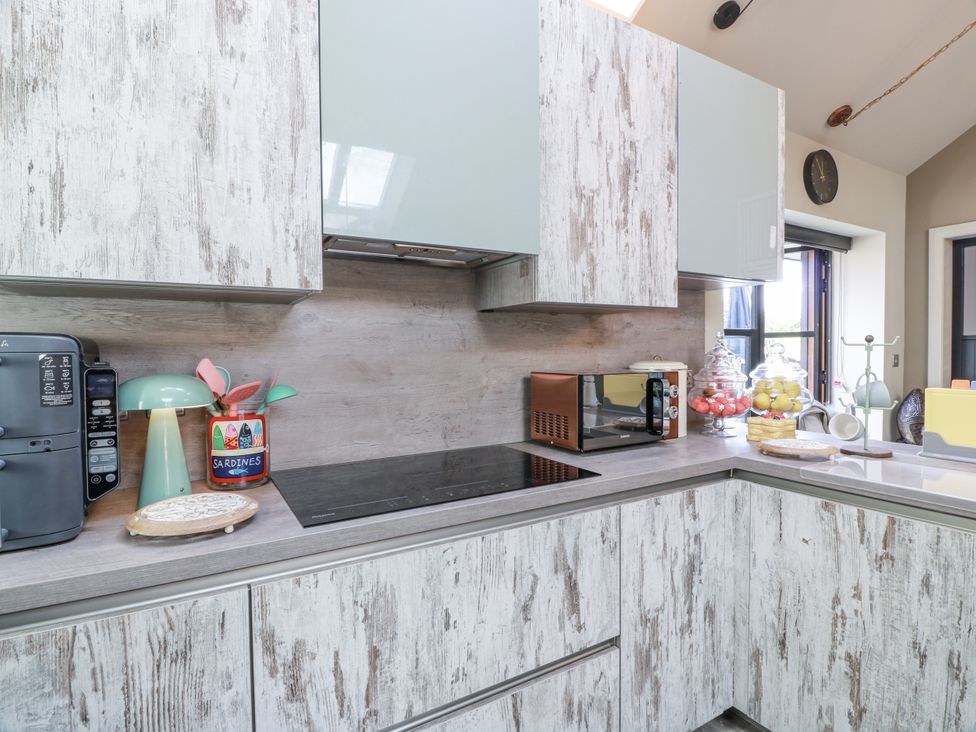 A kitchen with cabinets, a coffee maker, a lamp, a microwave, and a fruit bowl at Scotia At The Brig in Annan