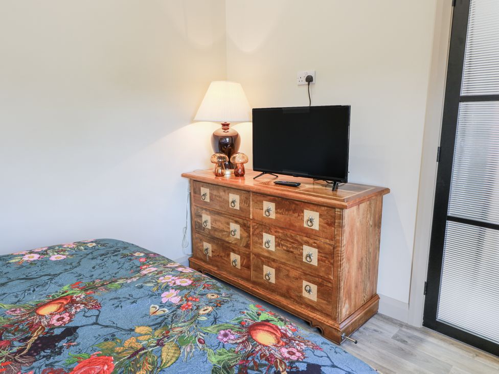 A bedroom with a dresser, TV, and lamp at Scotia At The Brig Annan
