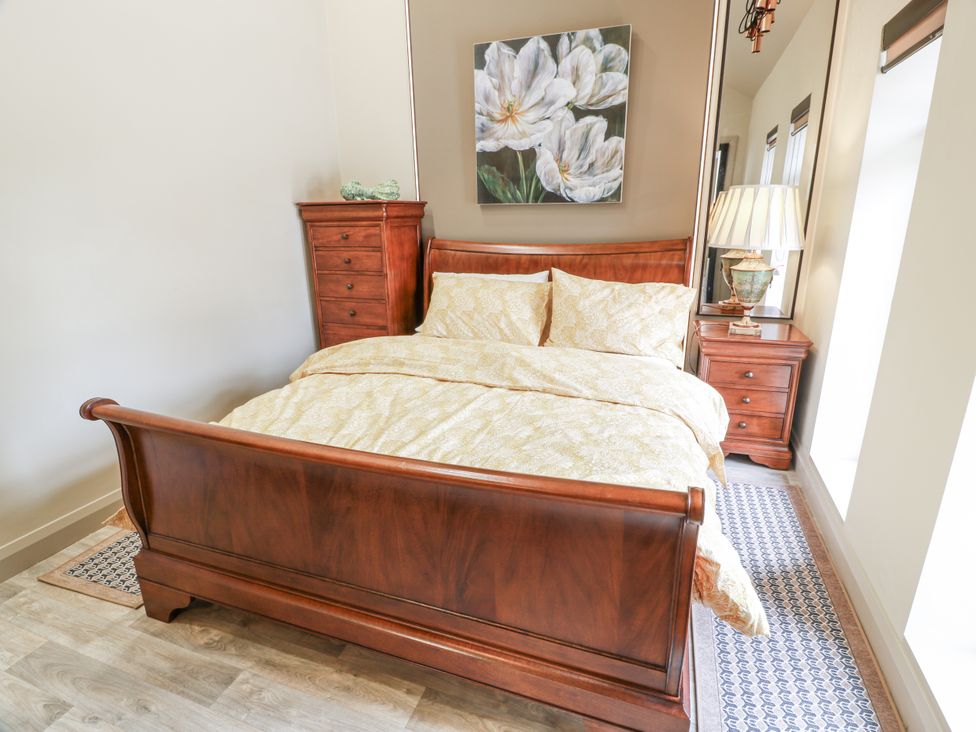 A bedroom with a wooden bed and nightstand at Scotia At The Brig Annan