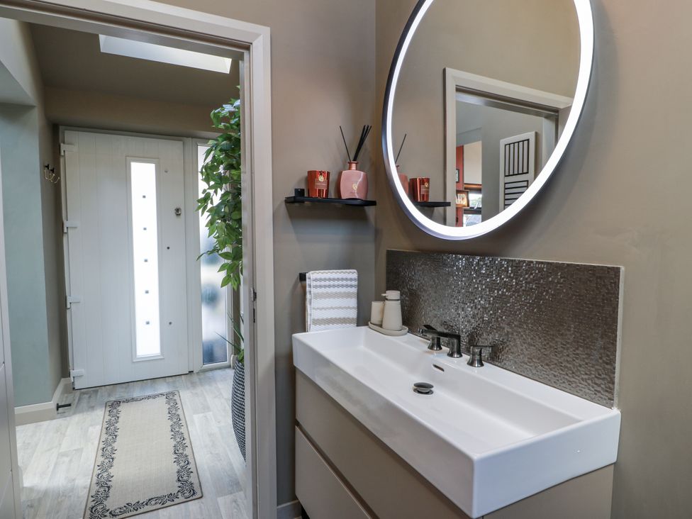 A bathroom featuring a sink, mirror, and door at Scotia At The Brig Annan