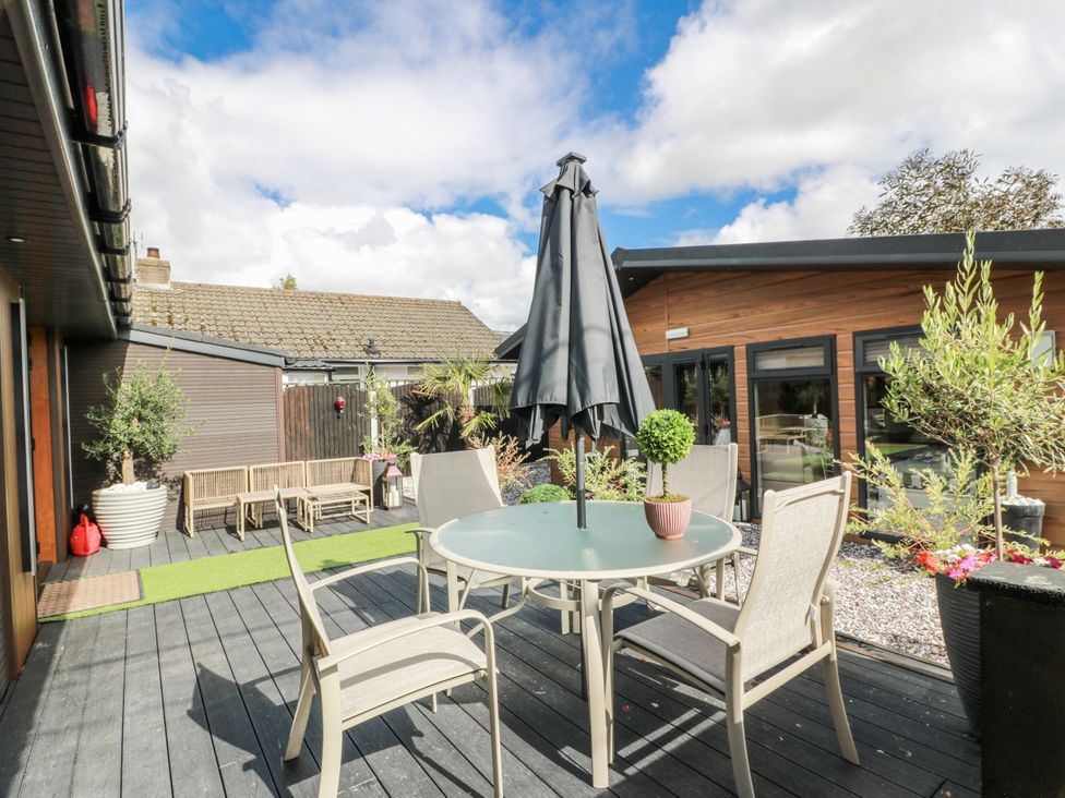 An outdoor area with a table and chairs under an umbrella at Scotia At The Brig Annan