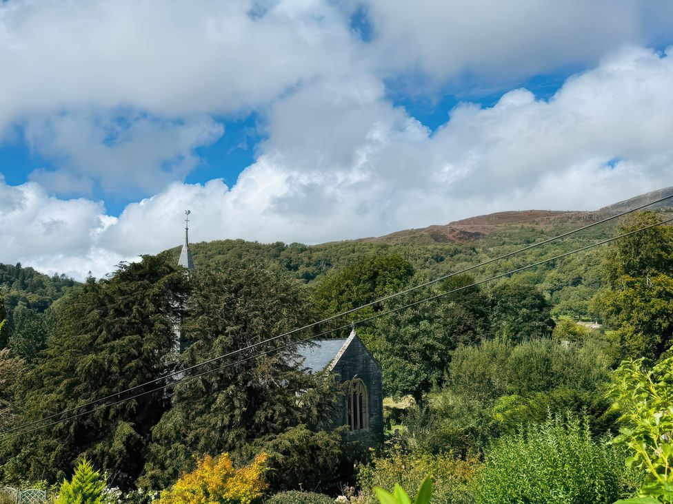 A view of a church surrounded by trees with mountains in the background at The Old Post Office null