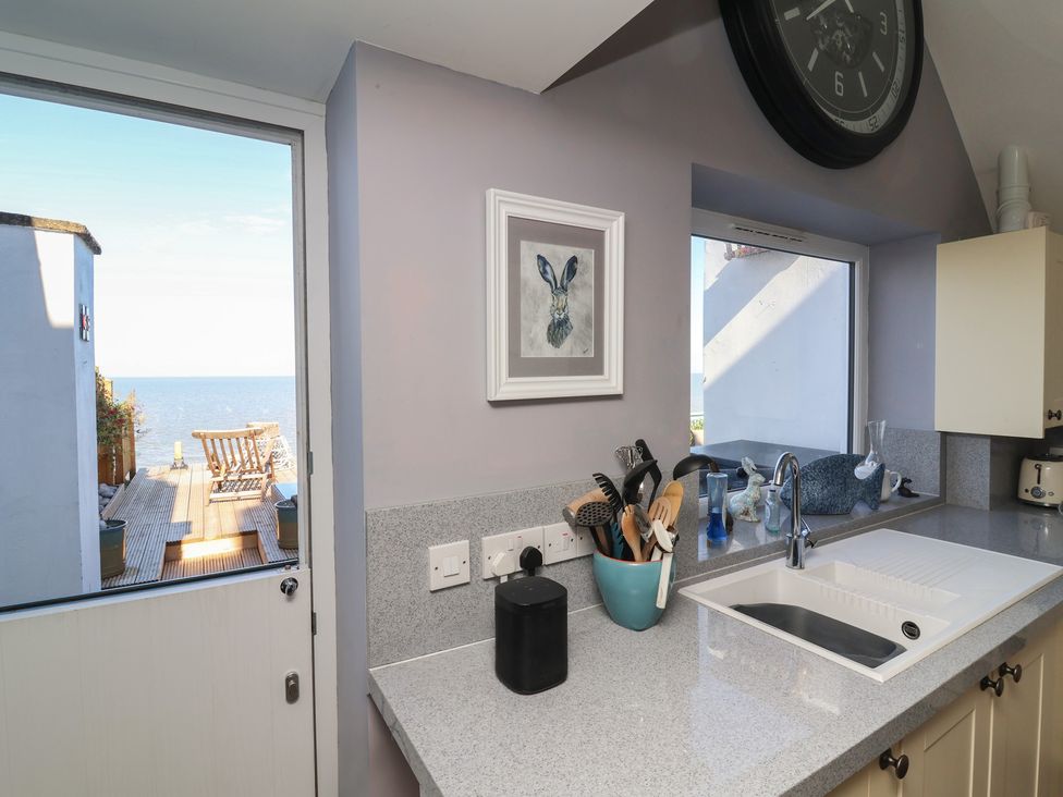 A kitchen with a view of the sea and utensils at Lenny's Place in Watchet