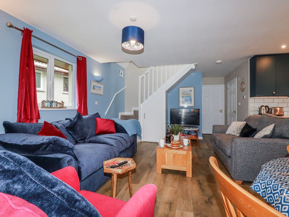 A living room with a sofa and television at Mayfly Lodge in St Tudy