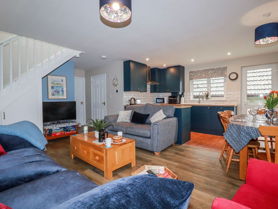 A living room with a kitchen and dining area at Mayfly Lodge St Tudy